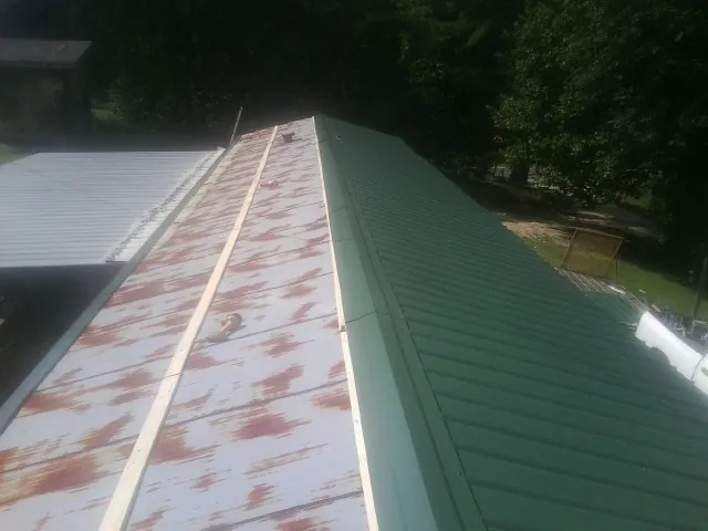 Old rusted panels beside newly installed green metal roofing — Wind Damage Roof Repair by Roofing Brothers in Mountainside
