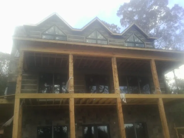 Dormers and porch framing on a large log home under construction — Roof Coating work by our crew in Mountainside