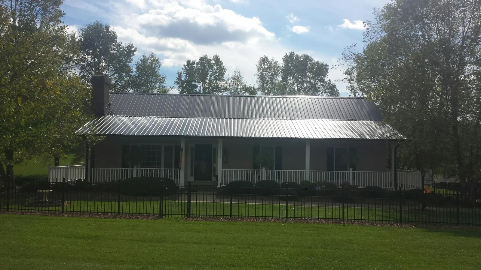 Gray metal roof on a brick ranch with a full width front porch — Gutter Guard Installation work by our crew in Mountainside