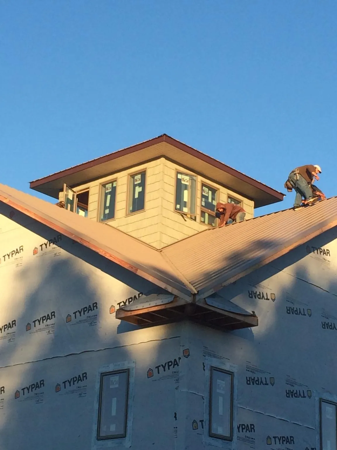 Roofers working around a rooftop cupola on a new metal roof at sunset — Roof Waterproofing in Mountainside by Roofing Brothers